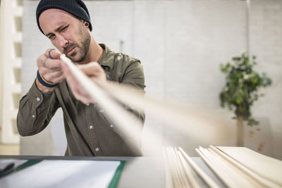 Young man working with wood at desk in office