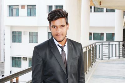 Portrait of man in suit standing against buildings