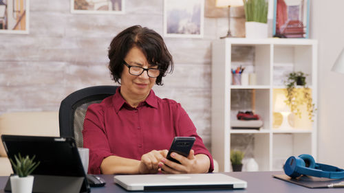 Young woman using mobile phone while sitting on table