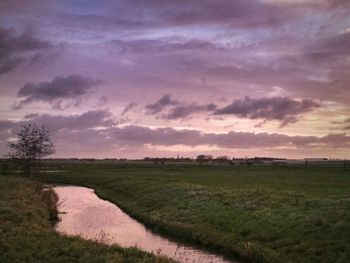 Scenic view of grassy field against cloudy sky