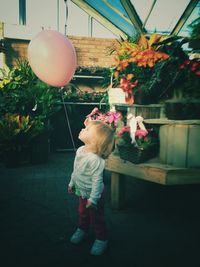 Girl with balloon standing against plants