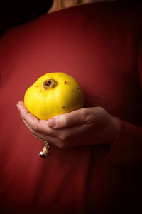 Woman in a tile-colored dress, and quince in hand