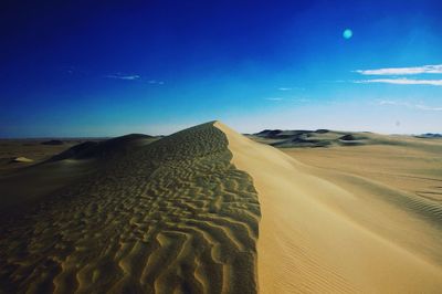 Scenic view of desert against blue sky