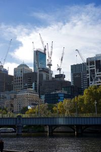 Bridge over river by buildings against sky in city