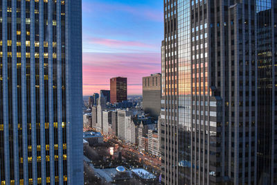 Modern buildings in city against sky during sunset