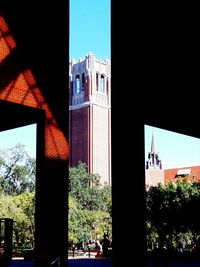 Low angle view of trees and buildings against clear sky