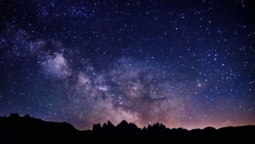 Low angle view of silhouette mountains against star field