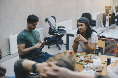 Computer programmers sitting with snacks at desk in office