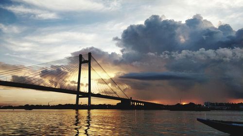 Bridge over river against cloudy sky