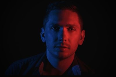 Close-up portrait of young man against black background