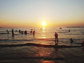 Silhouette people on beach against sky during sunset