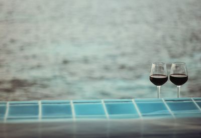 Close-up of wineglasses by swimming pool