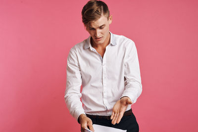 Young man holding paper against colored background