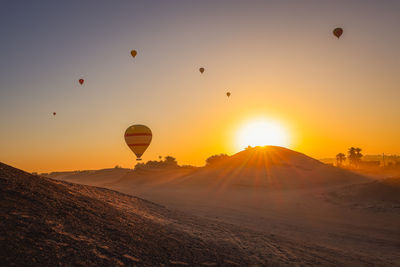 Hot air balloons flying against sky during sunset