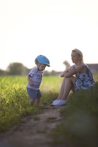 Rear view of mother and daughter walking on field