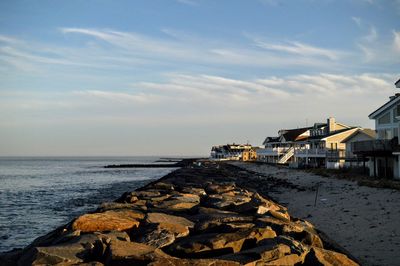 Built structures by calm sea and against sky