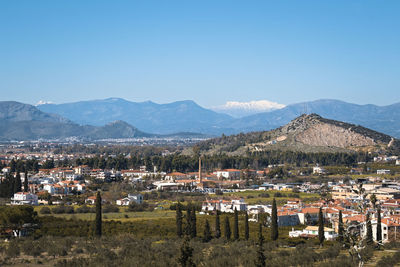 High angle view of townscape and mountains against clear blue sky
