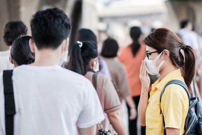 Woman with surgical mask by crowd in city