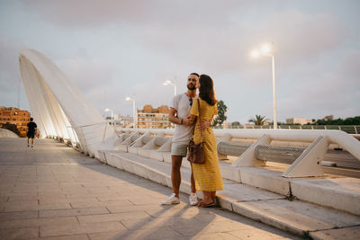 Woman kissing man on footpath