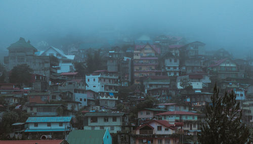 Low angle view of buildings on mountain during foggy weather