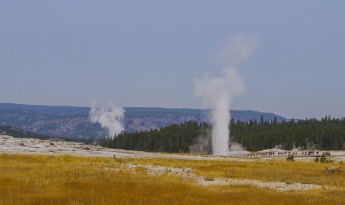 Steam emitting from volcanic landscape against clear sky