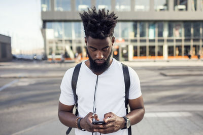 Young man using phone while in city