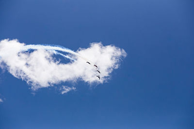 Low angle view of airplane flying against blue sky airshow