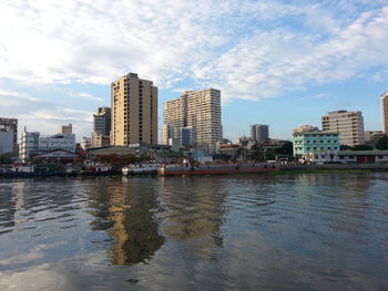 Canal by buildings in city against sky