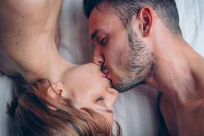Directly above shot of couple kissing on bed at home