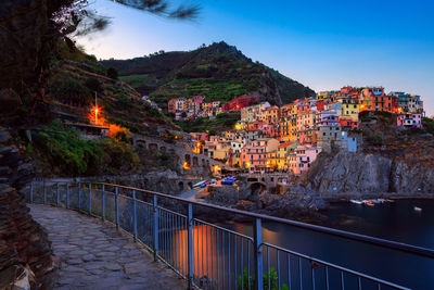 Illuminated buildings in town against sky at dusk