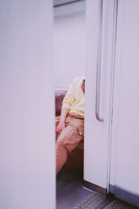 Woman sitting on door of building at home