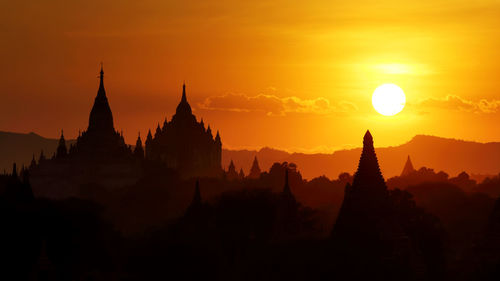 Silhouette temples against sky during sunset