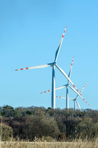 Low angle view of windmills on field against clear sky