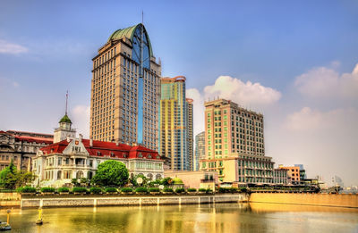 Buildings at waterfront against cloudy sky