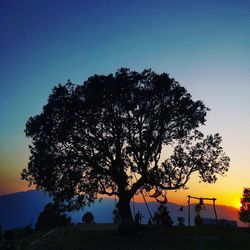 Silhouette tree on field against clear sky at sunset