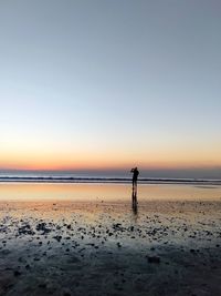Silhouette person on beach against sky during sunset