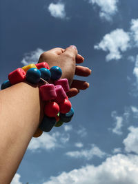 Close-up of hand holding multi colored against sky