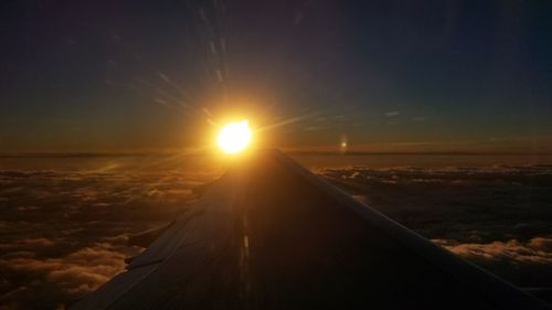 Airplane wing against sky during sunset