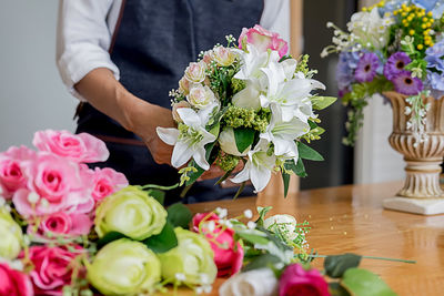 Midsection of woman arranging flowers in bouquet 