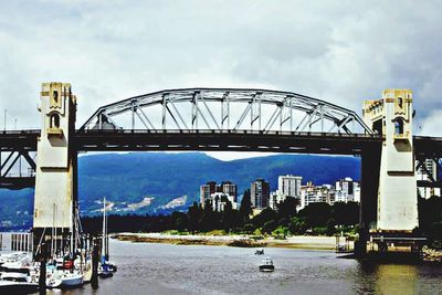 Bridge over river against cloudy sky