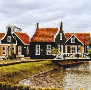 Houses by river against sky