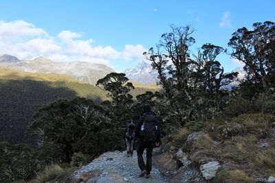 Rear view of people walking on mountain against sky