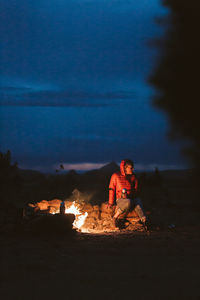 People sitting on bonfire against sky at night