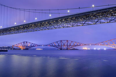 Illuminated bridge over river at night