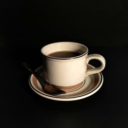 Close-up of coffee cup on table against black background