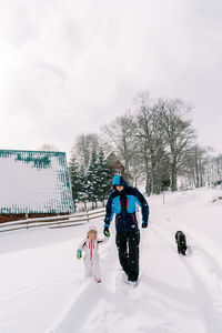 Rear view of man walking on snow covered landscape