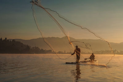 Fishing net on lake against sky during sunset