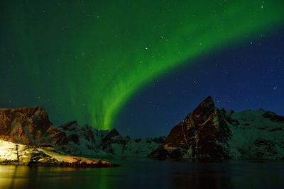 Scenic view of lake and mountains against sky at night