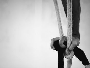 Close-up of man holding rope against wall