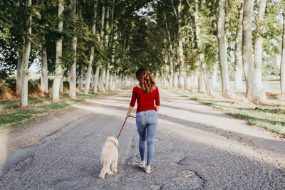 Full length of a man walking with dog on road